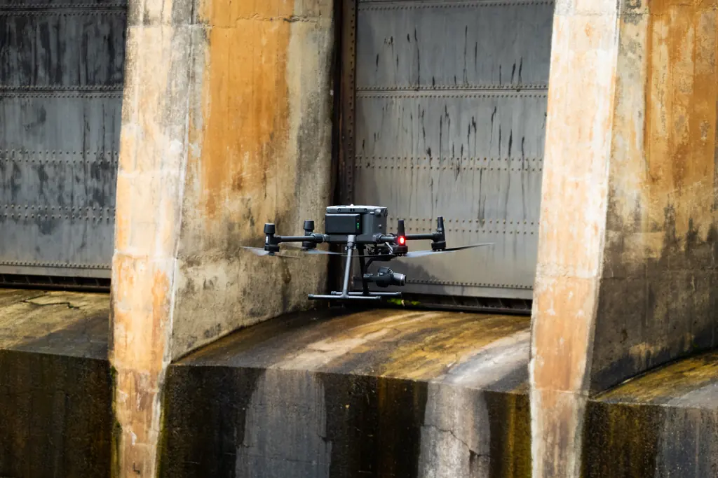 Drone inspecionando sob os pilares de uma barragem